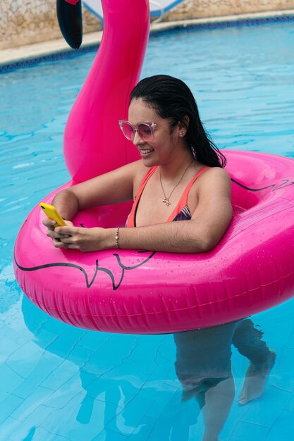 Young woman in a bathing suit checking her cell phone at a swimming pool in summertime