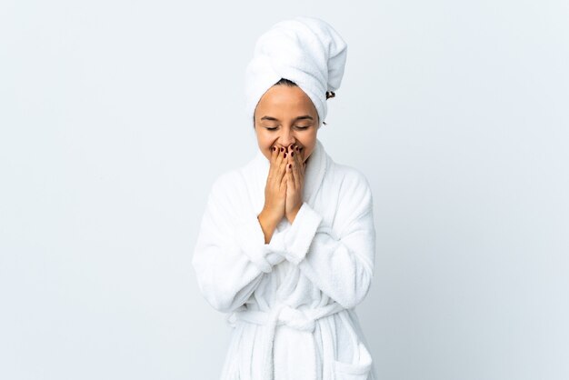 Young woman in bathrobe over isolated white wall happy and smiling covering mouth with hands