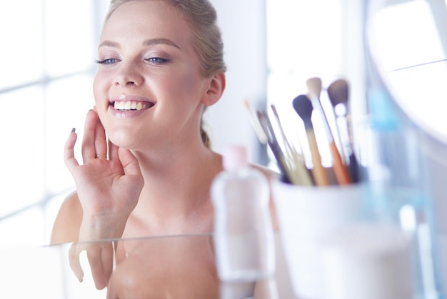 Young woman in bathrobe looking in bathroom mirror