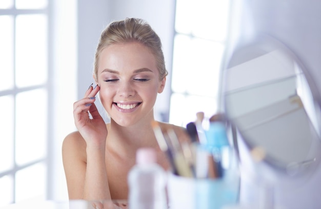 Young woman in bathrobe looking in bathroom mirror