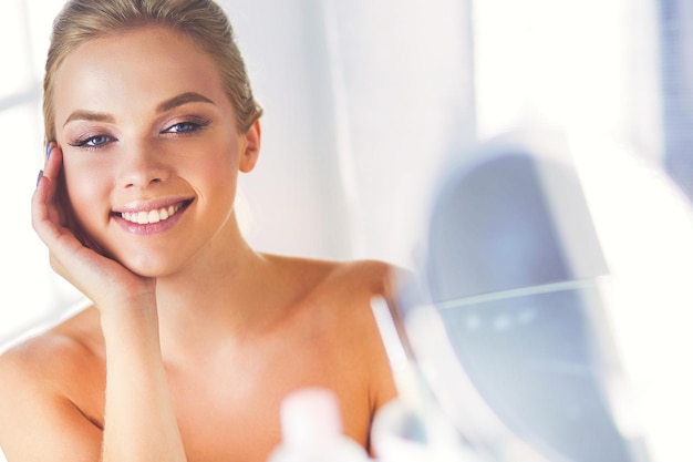  Premium Photo | Young woman in bathrobe looking in bathroom mirror