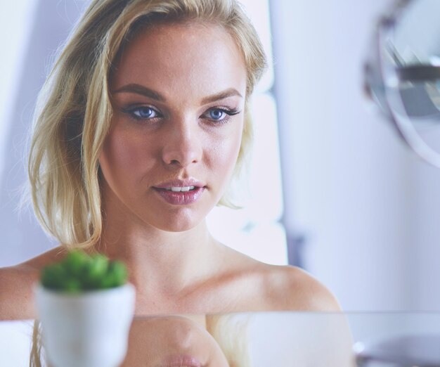 Young woman in bathrobe looking in bathroom mirror