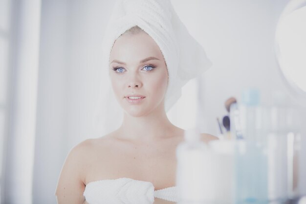 Young woman in bathrobe looking in bathroom mirror