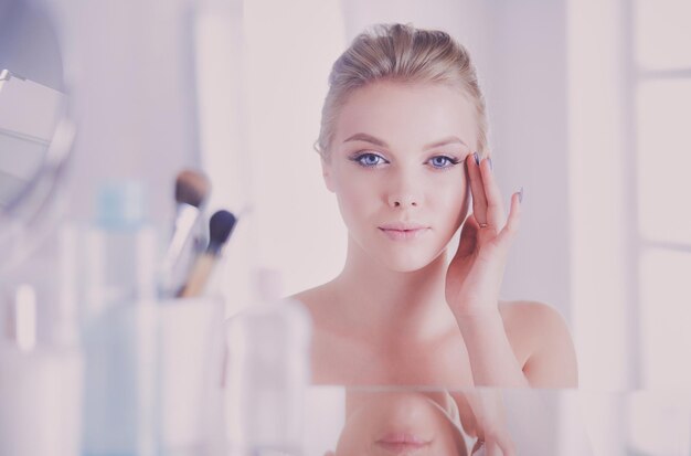  Premium Photo | Young woman in bathrobe looking in bathroom mirror