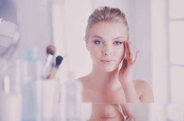 Young woman in bathrobe looking in bathroom mirror