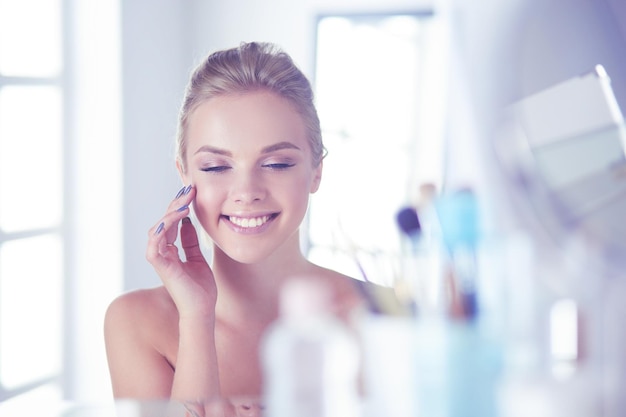 Young woman in bathrobe looking in bathroom mirror