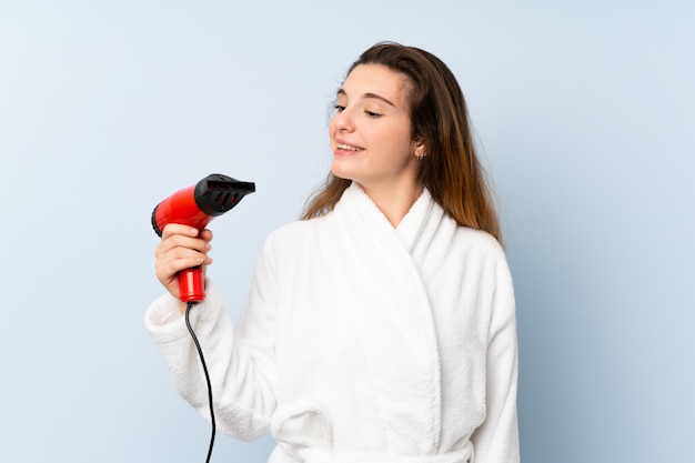 Young woman in a bathrobe with hair hairdryer with happy expression