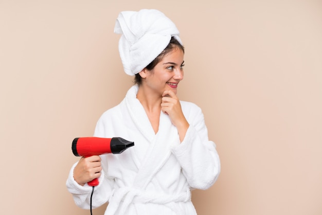 Young woman in a bathrobe with hairdryer looking side