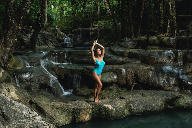 Young and woman on the beautiful waterfall in the jungle