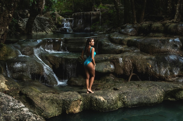 Young and woman on the beautiful waterfall in the jungle