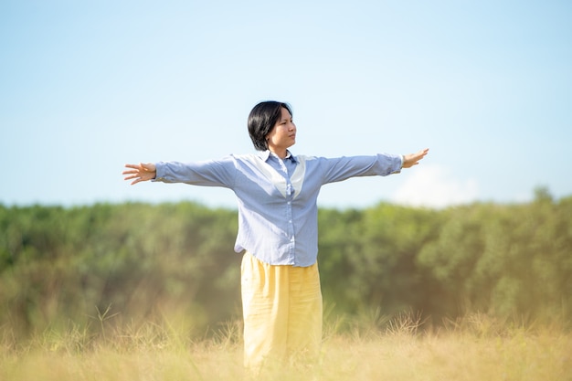 空の背景の美しい牧草地で幸せな若い女性美しい女性。幸福の概念。