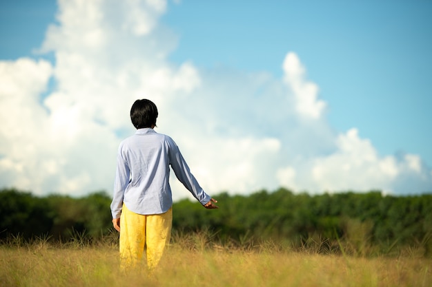 空の背景の美しい牧草地で幸せな若い女性美しい女性。幸福の概念。