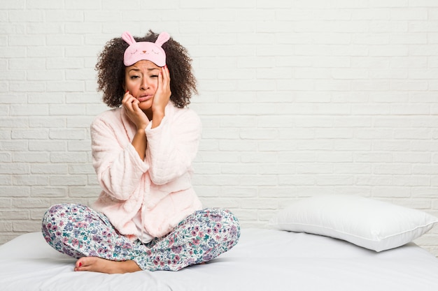 Young woman in the bed wearing pijama whining and crying disconsolately.