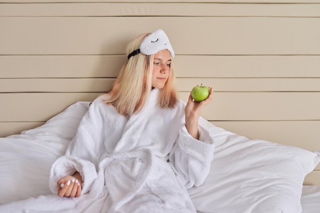 Young woman in bed with green apple