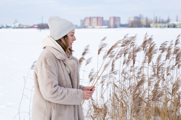 A young woman in a beige dress of neutral colors collects pampas grass