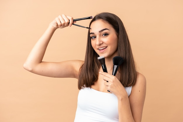 Young woman on beige holding makeup brush