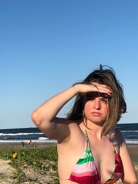 Young woman in bikini on beach against clear sky