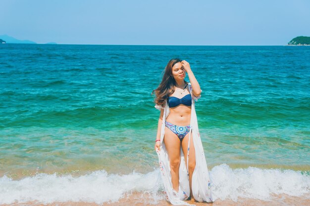 Young woman in bikini on beach against sky