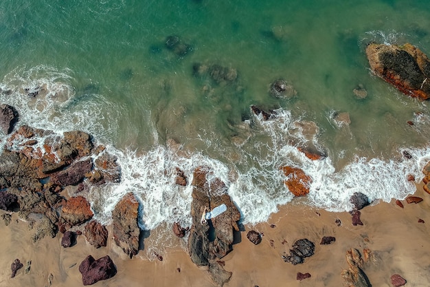 Young woman in a bikini and pareo with long train lying on the back on the sand near the waves of blue sea top view