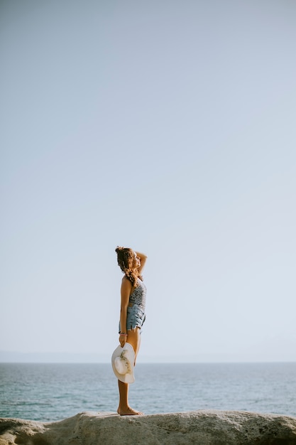 Young woman in bikini standing on rocks by the sea