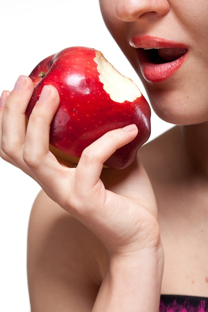 Молодая женщина кусает красное яблоко, изолированное на белом