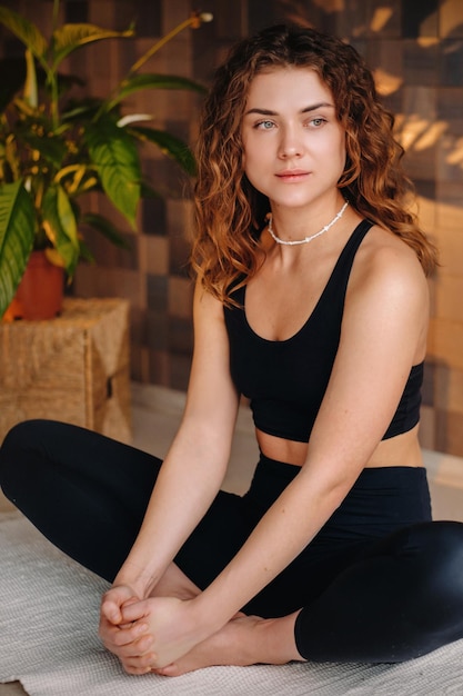 A young woman in black clothes is doing yoga in a modern gym.The concept of health.