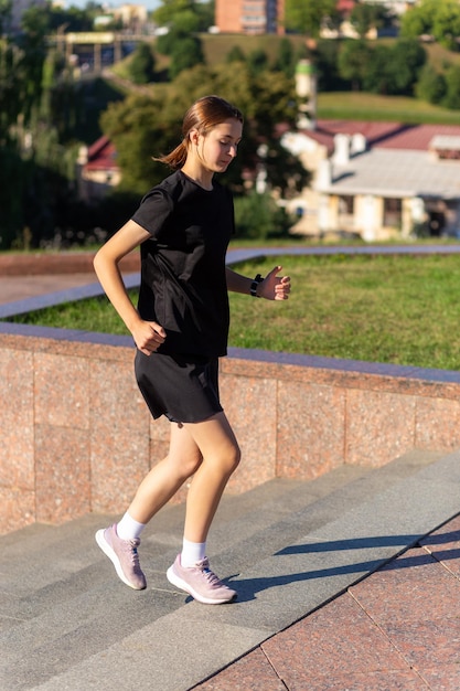 A young woman in black clothes running on stairs at city street early morning