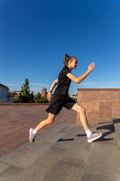 A young woman in black clothes running on stairs at city street early morning