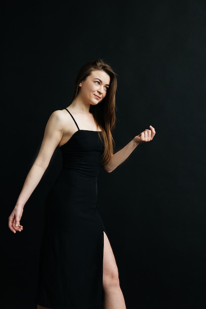 Young woman in black dress on black background. Girl on dark