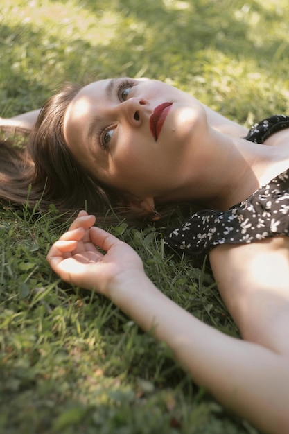 Photo young woman in black dress lying on green grass selective focus