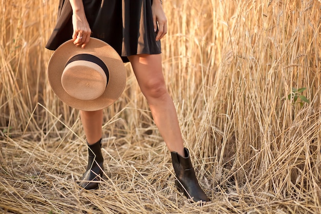 Young woman in black dress standing in field with wheat