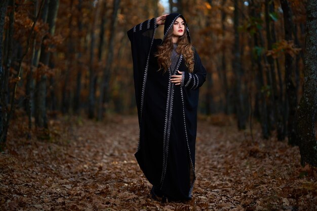 Young woman in black dress with hood in the oak forest