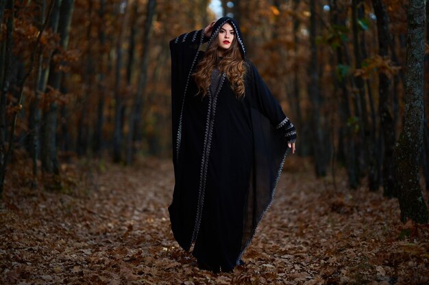 Young woman in black dress with hood in the oak forest