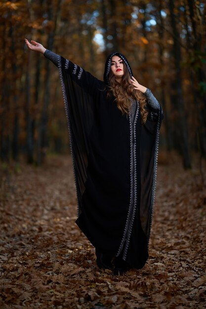 Young woman in black dress with hood in the oak forest