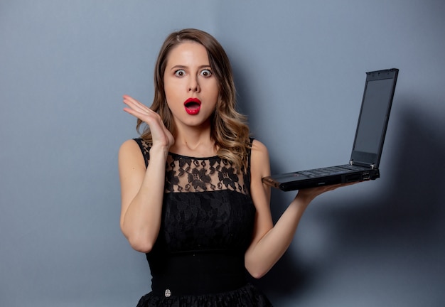 Young woman in black dress with notebook on grey wall