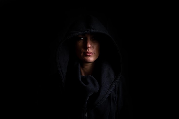 Photo young woman in a black hood on a black background