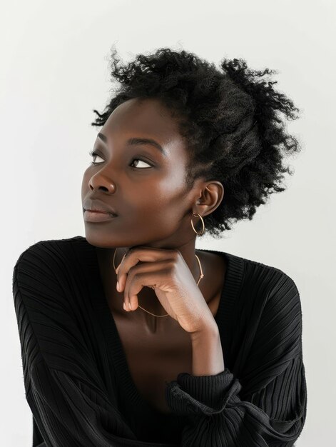 Photo a young woman in a black outfit looks off into the distance with a reflective gaze her afrotextured hair elegantly styled showcasing natural beauty and contemplation