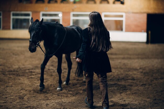 Young woman in black runs to her horse at ranch