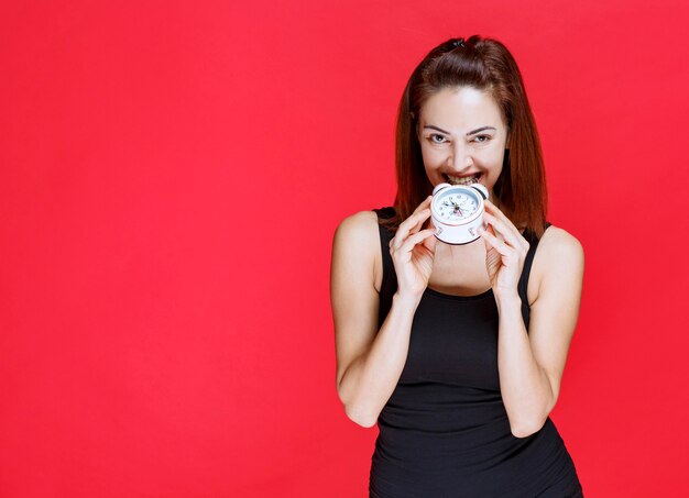 Young woman in black singlet holding an alarm clock