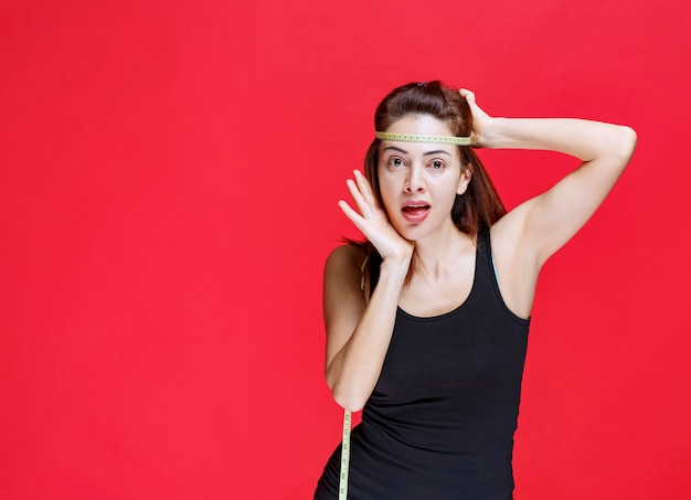 Young woman in black singlet holding a measuring tape