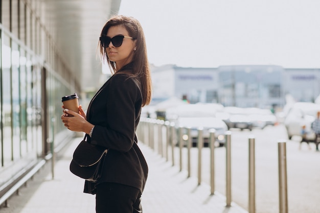 Giovane donna in abito nero che beve caffè