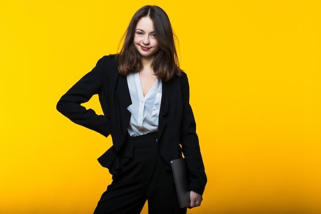 A young woman in a black suit with a laptop in her hands