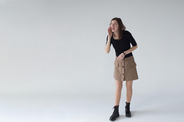 A young woman in a black Tshirt on a white background looks like an empty space holding her hand