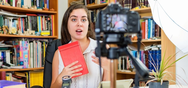Photo young woman blogger recording video at home about books