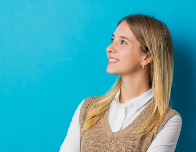 Young woman blonde standing watching to side arm crossed blue background