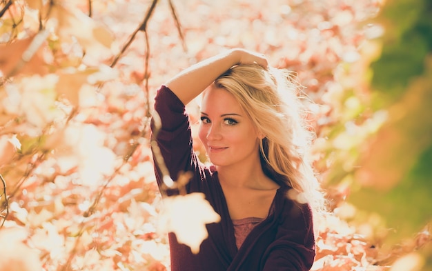 Young woman blonde with autumn leaves in hand and fall yellow