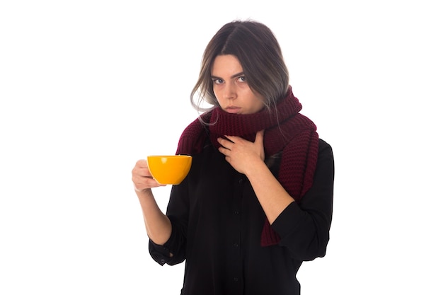 Young woman in blouse with long vinous scarf holding a yellow cup on white background in studio