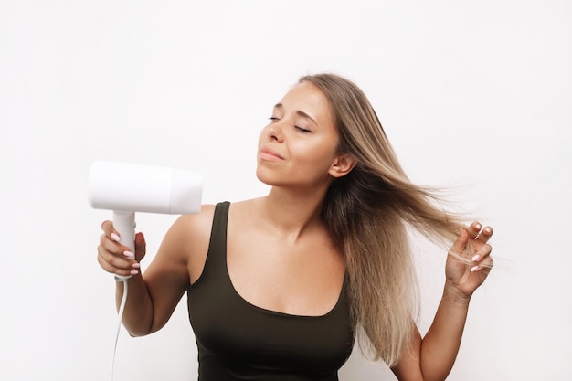 Young woman blow drying her hair isolated on a white background Hair styling