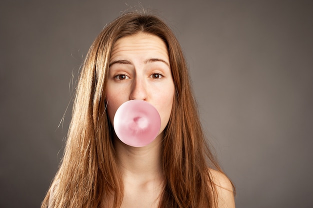 Young woman blowing a bubble from a chewing gum