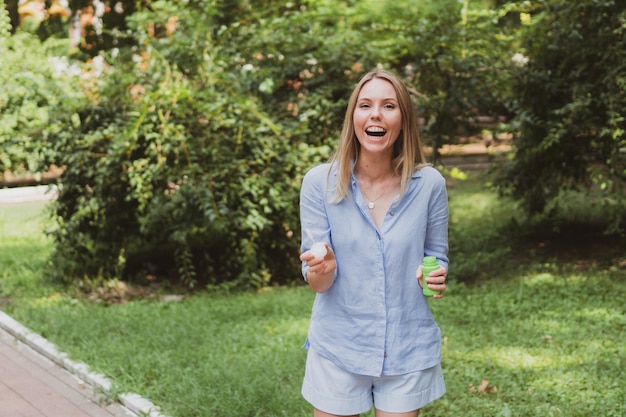 Young woman blowing bubbles in the park and having fun